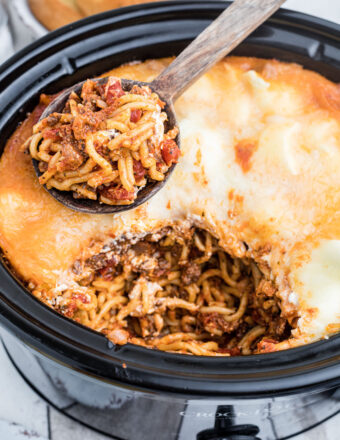 A serving spoon has removed a scoop of spaghetti from the Crockpot.