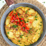 Tortilla Espanola in a skillet on a wicker placemat.