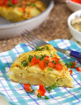 Spanish Tortilla slice on a plaid plate with bell pepper on top.