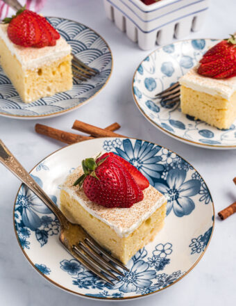 Three blue and white plates are topped with slices of tres leches cake.