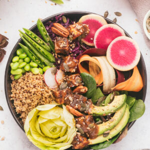 A vibrant vegan buddha bowl is placed on a white surface.