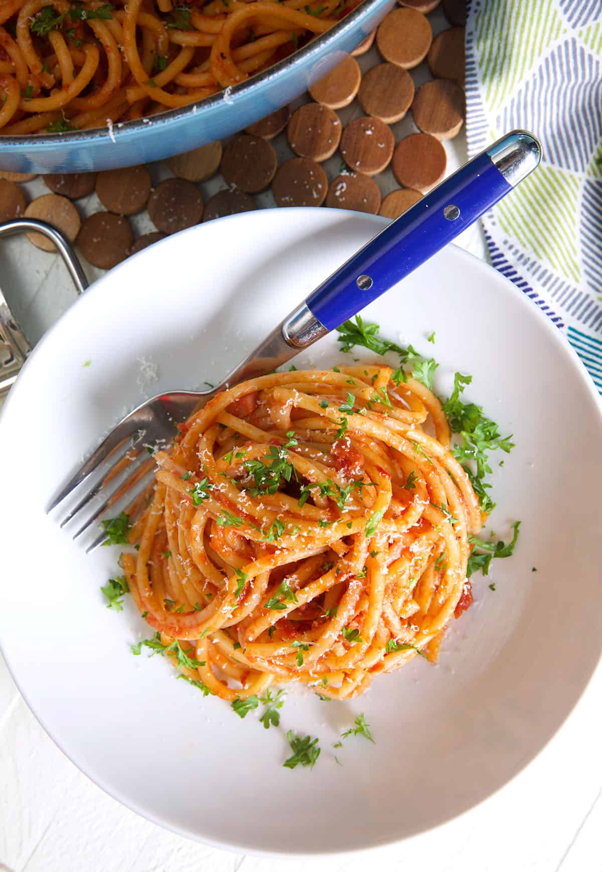 A serving of pasta with red sauce is garnished with fresh parsley.