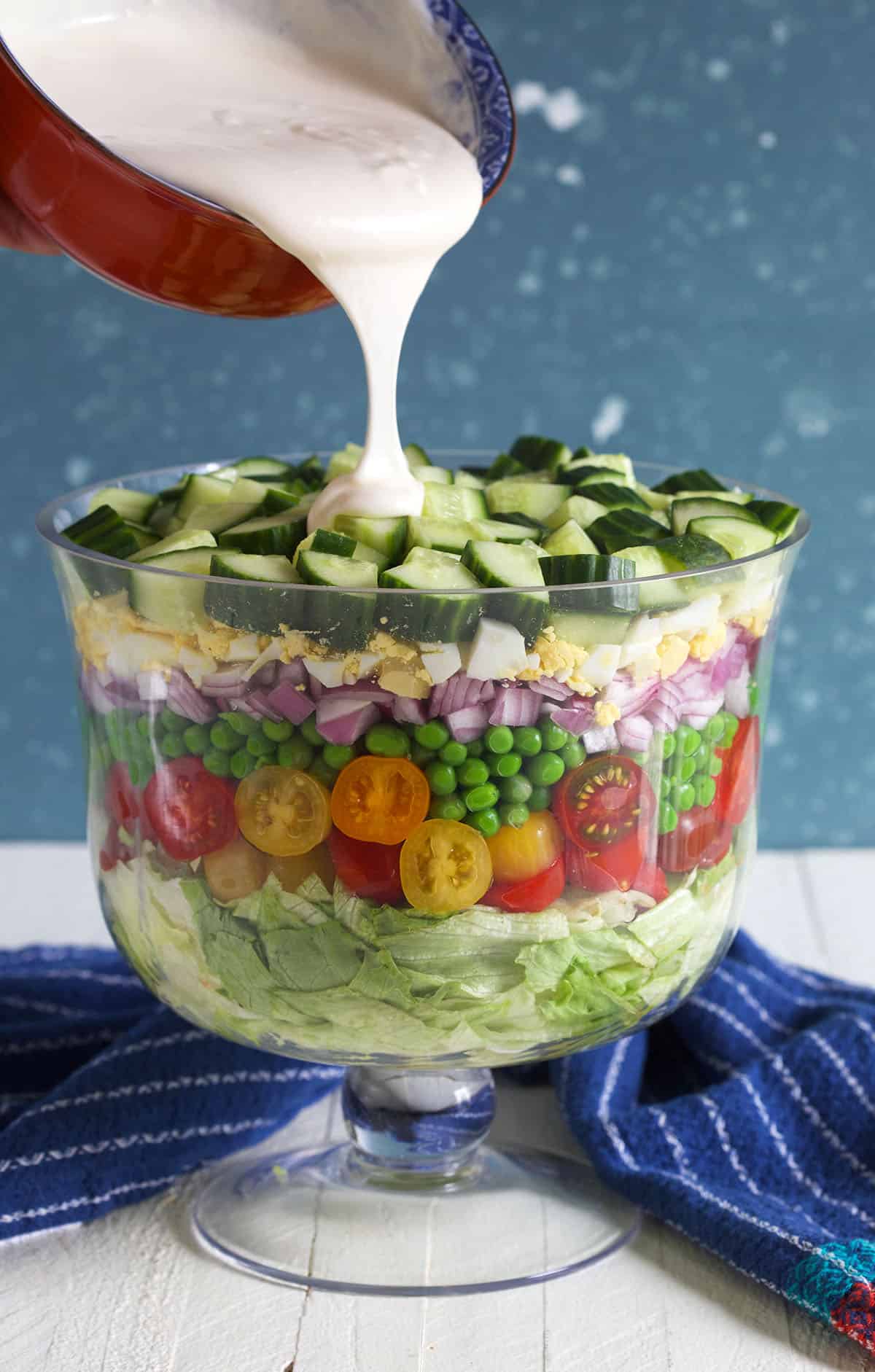 Dressing is being poured on top of an assembled salad.