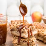 A spoon is drizzling caramel sauce onto a stack of two bars.