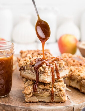 A spoon is drizzling caramel sauce onto a stack of two bars.