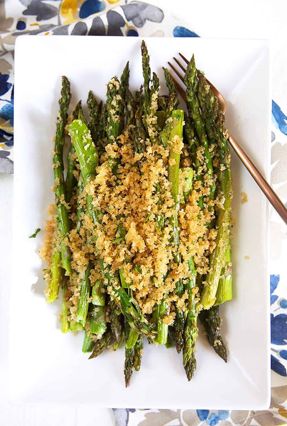 baked asparagus on a white platter.