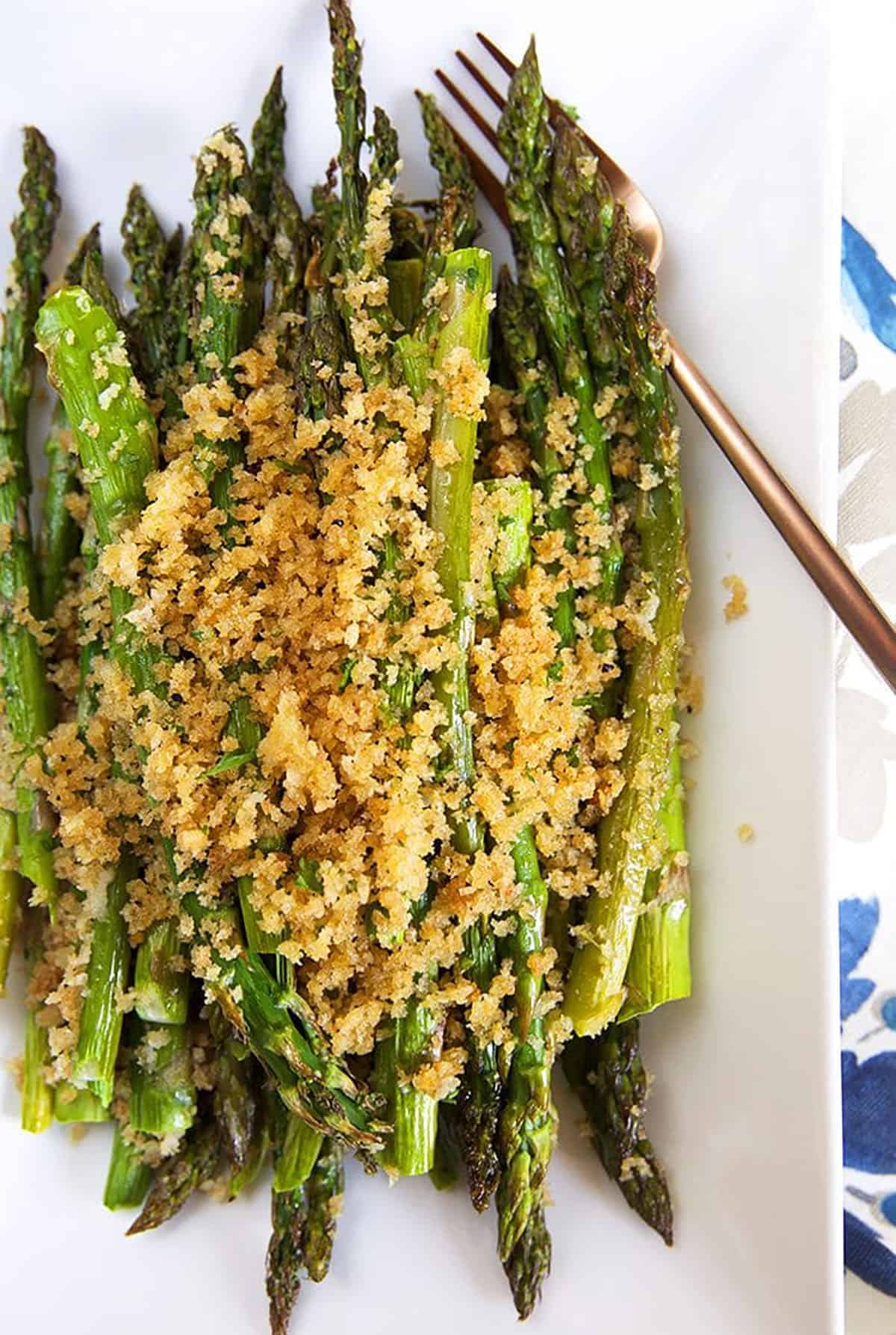 baked asparagus on a white platter with a crispy panko crust.