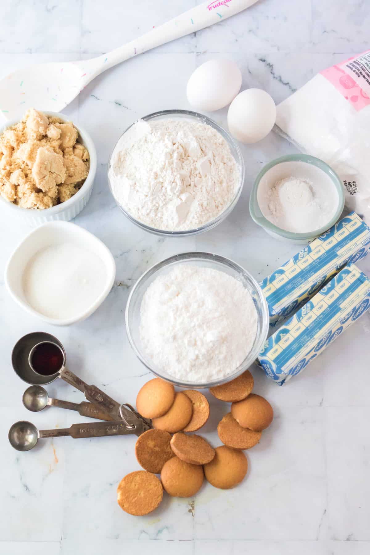 The ingredients for banana pudding cookies are spread out on a white countertop.