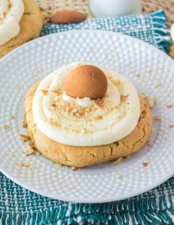 A single frosted banana pudding cookie is placed on a round white plate.
