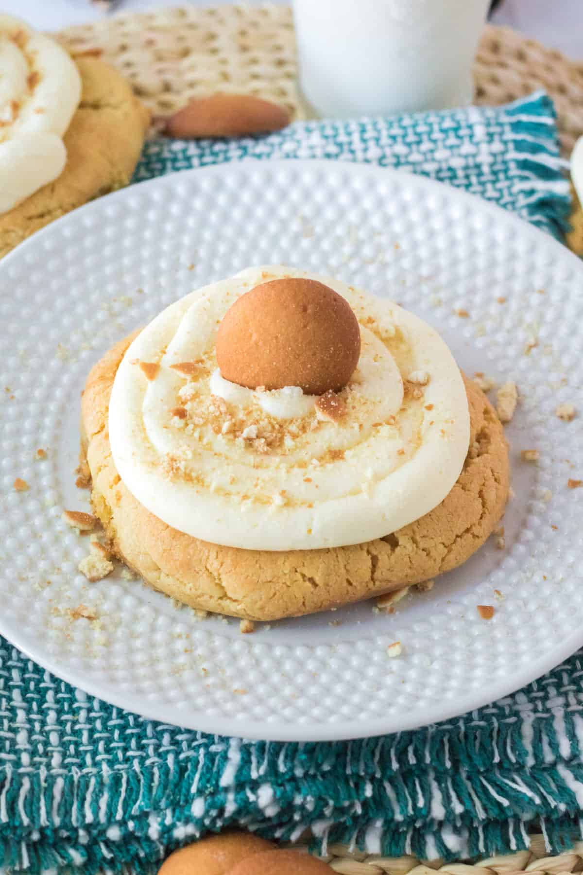 A single frosted banana pudding cookie is placed on a round white plate.