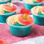 Blue pudding shots are topped with brown sugar, gummy bears, and candy peach rings.