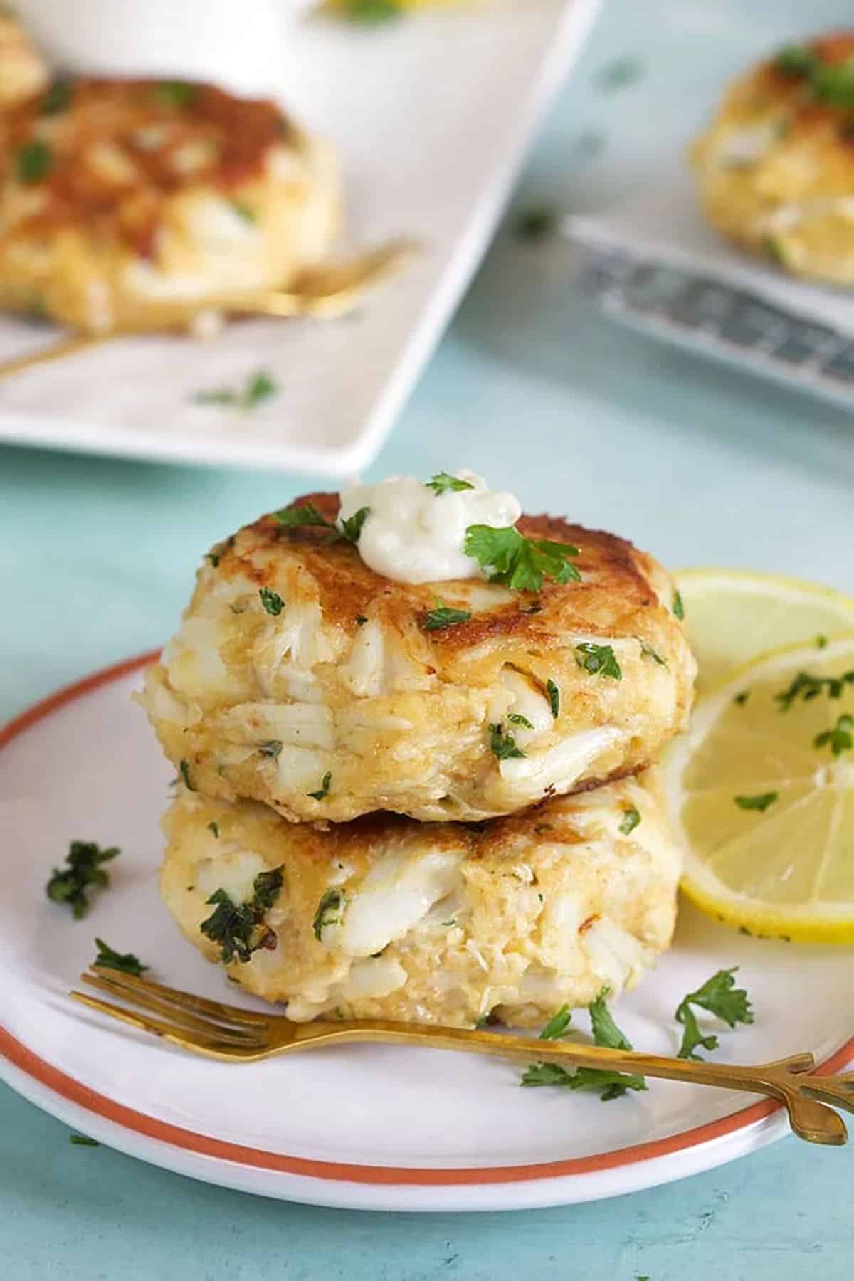 two crab cakes stacked on a white plate.