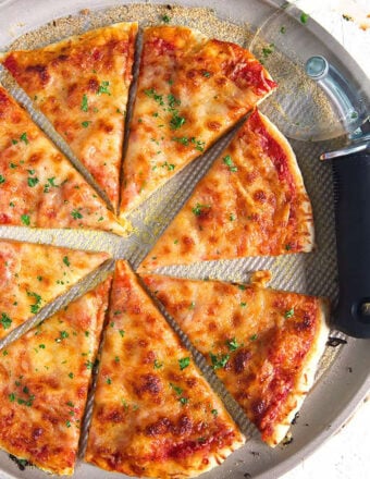 Thin Crust Pizza on a pizza pan with a pizza cutter.