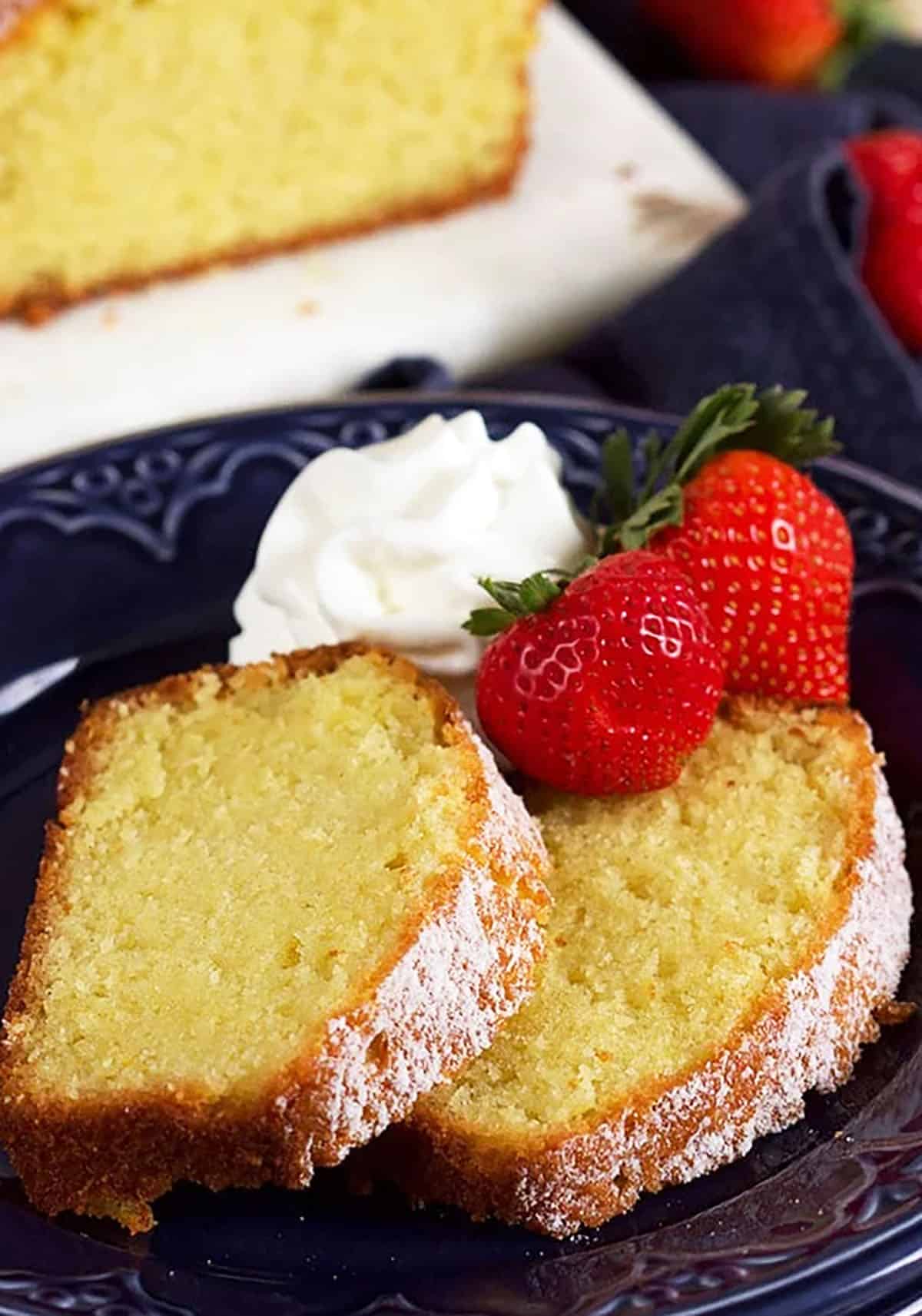 two slices of pound cake on a blue plate with whipped cream