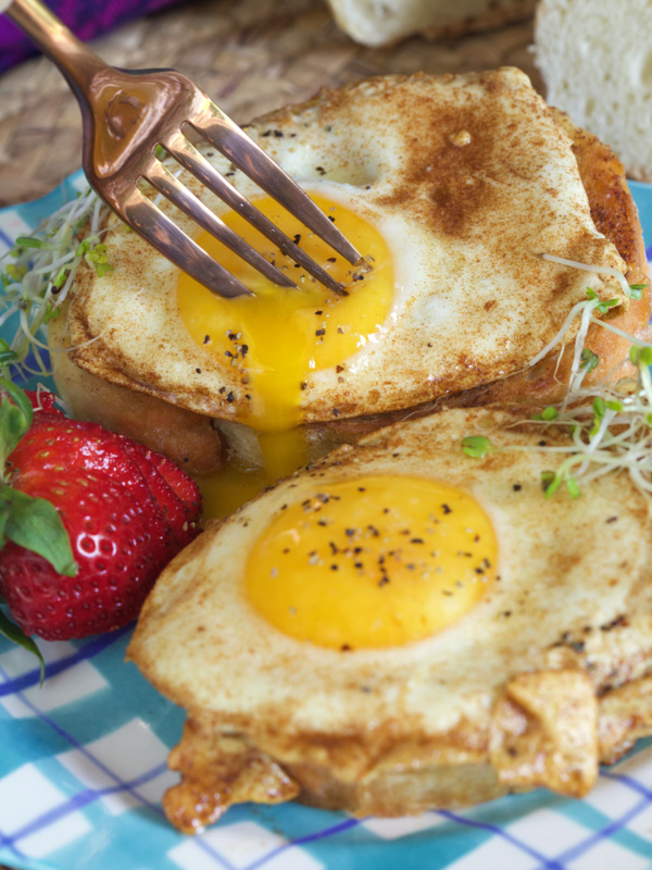 A fork is pushing into a basted egg on a piece of toast.