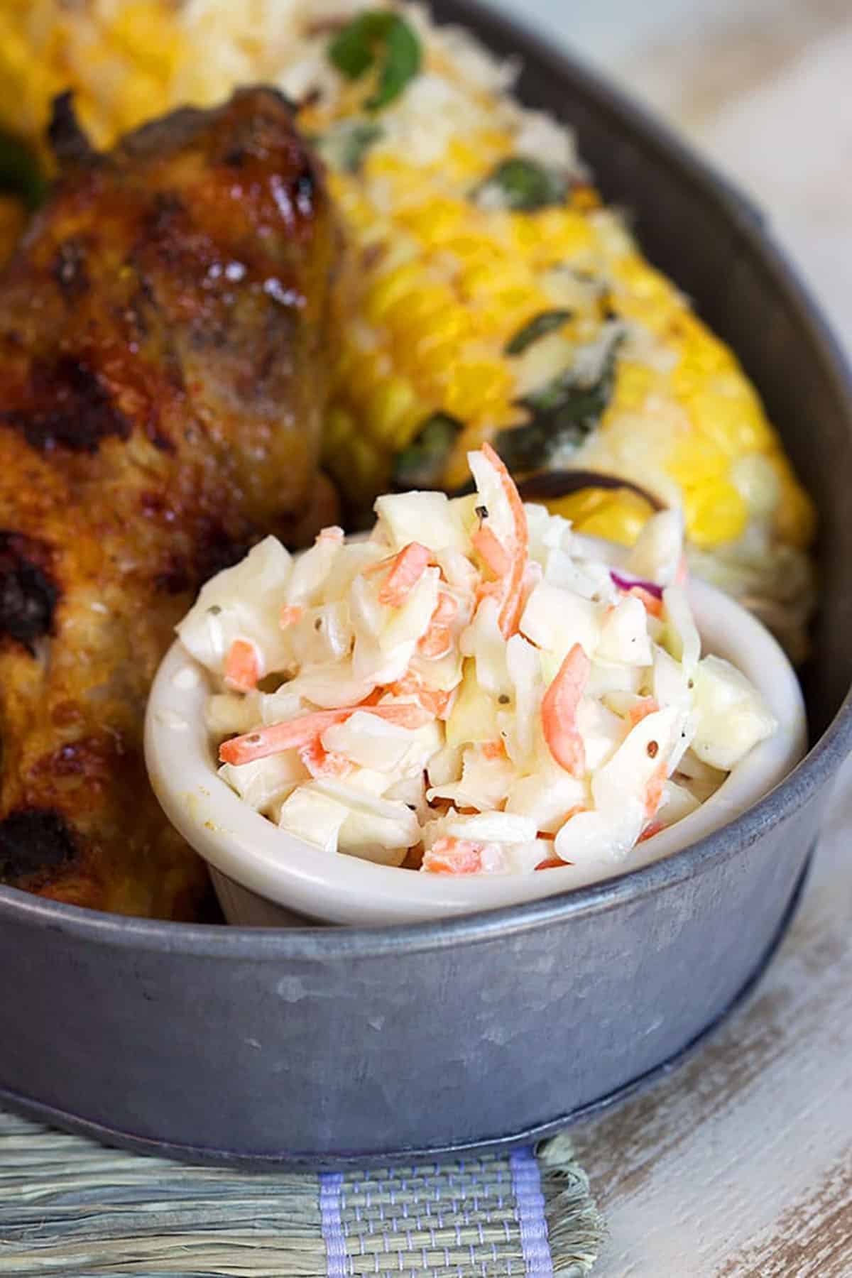 small white condiment dish filled with coleslaw in a tin with corn and chicken