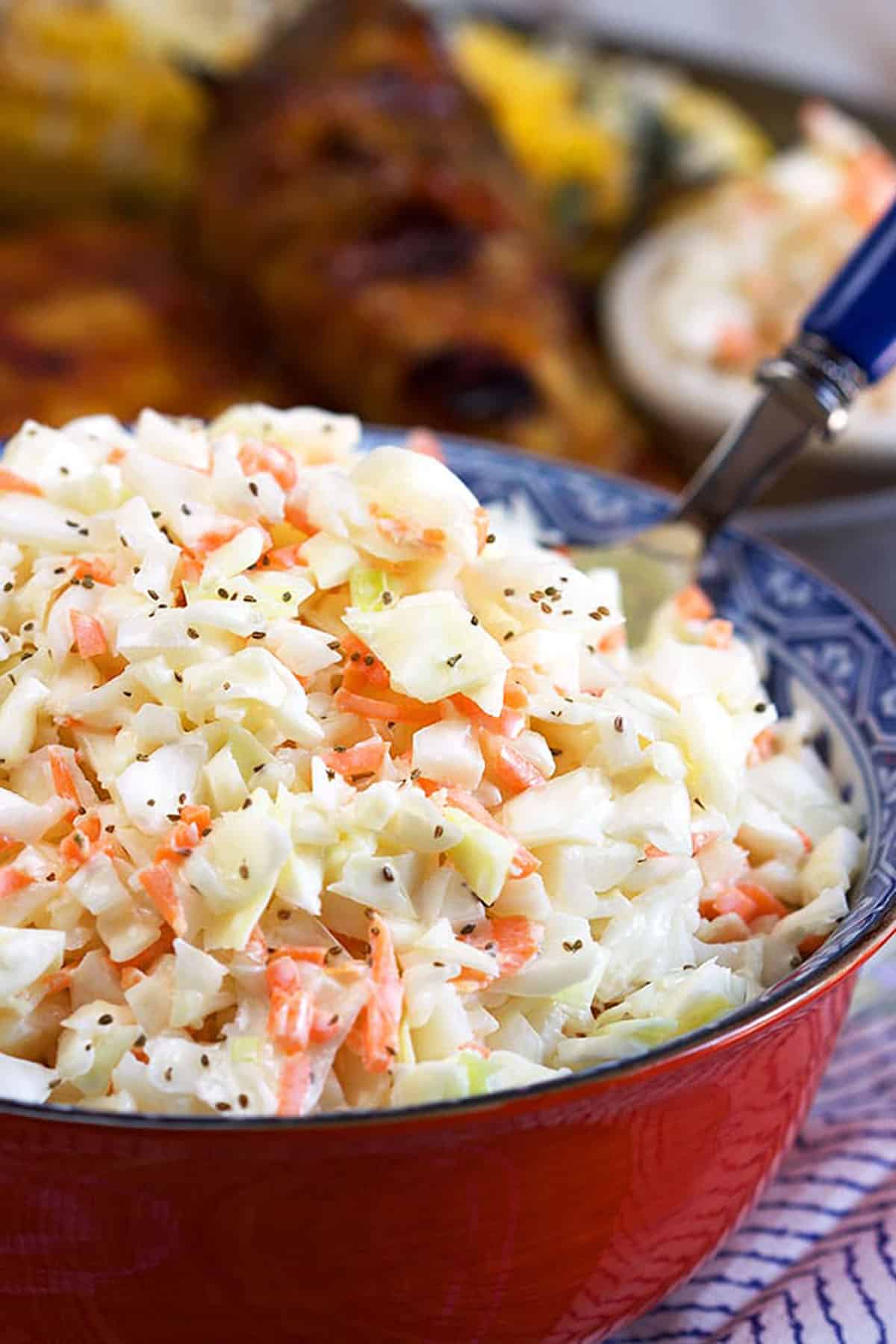 Coleslaw in a red bowl on a blue and white napkin.