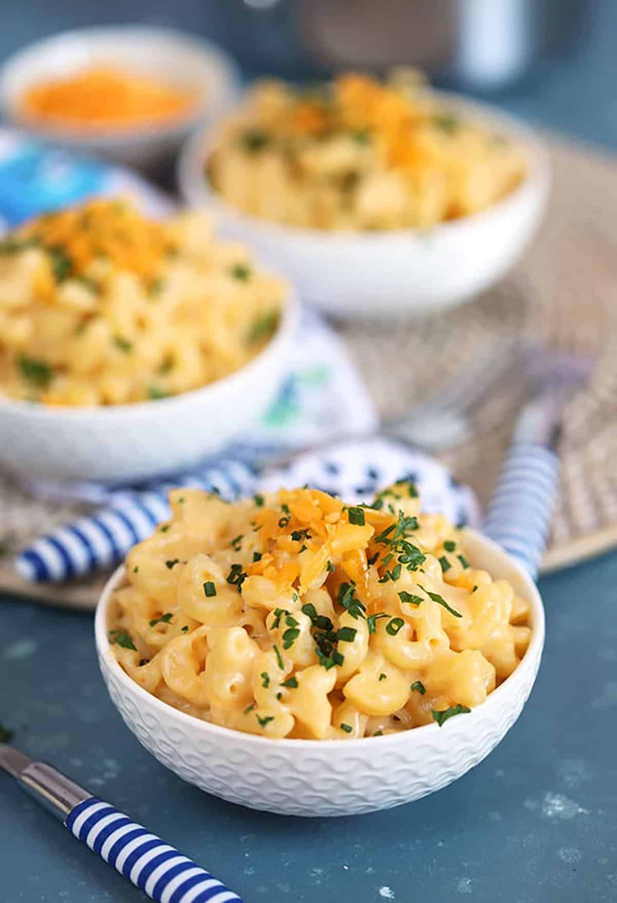 Easy Homemade macaroni and cheese in a blue thermos with dinosaurs on it and a fork digging in to take a bite 