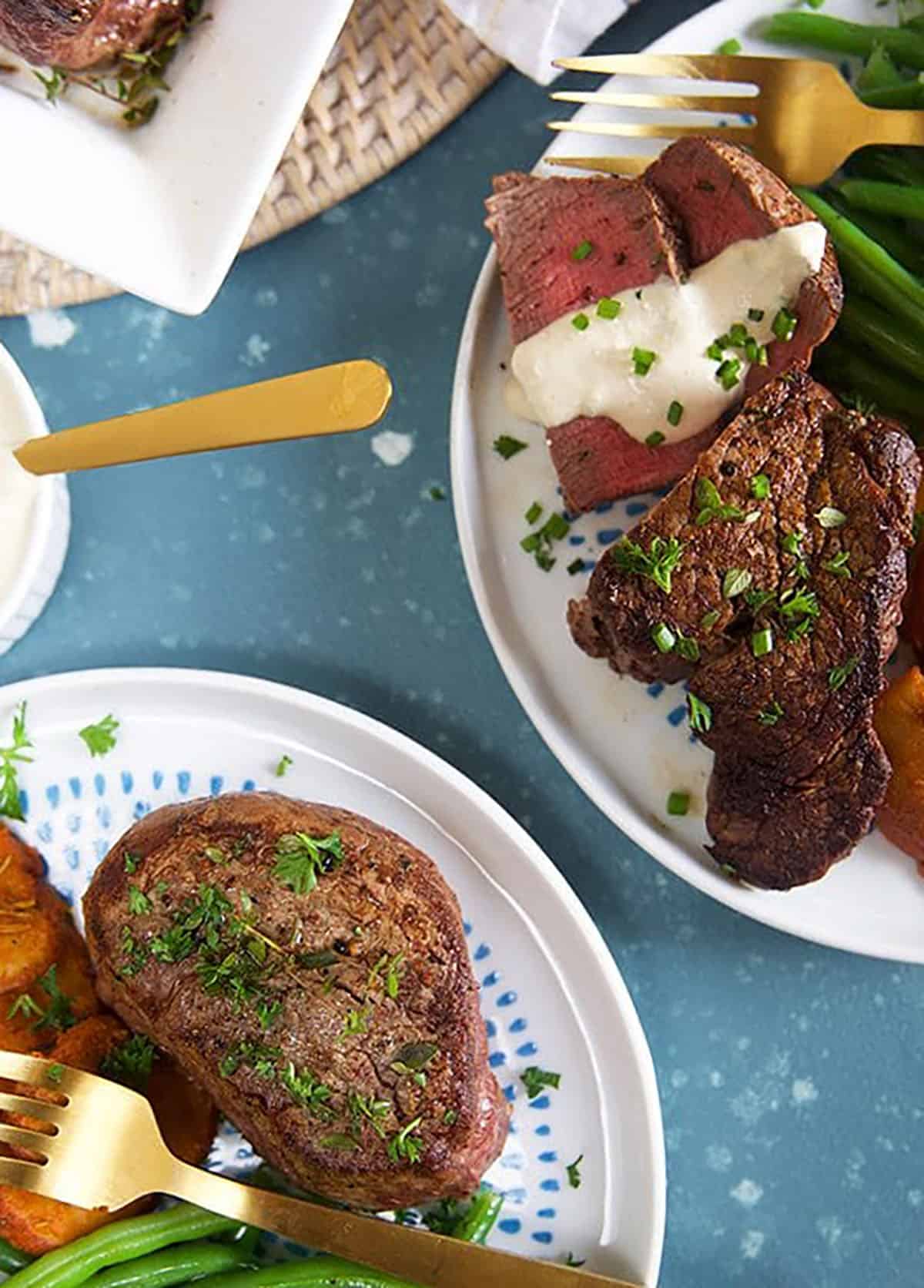 filet mignon on a white plate with horseradish sauce on top.