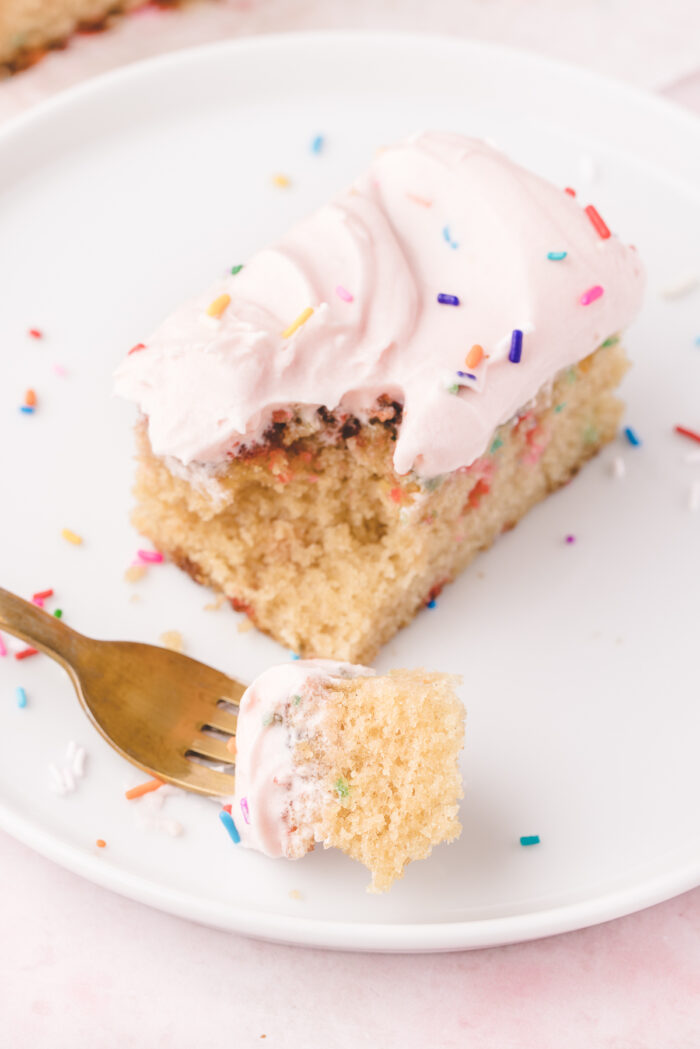 A fork has removed a bite sized portion of cake from a slice.