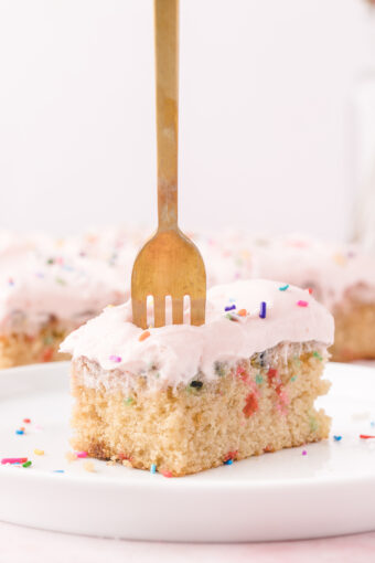 A fork is piercing a piece of cake.