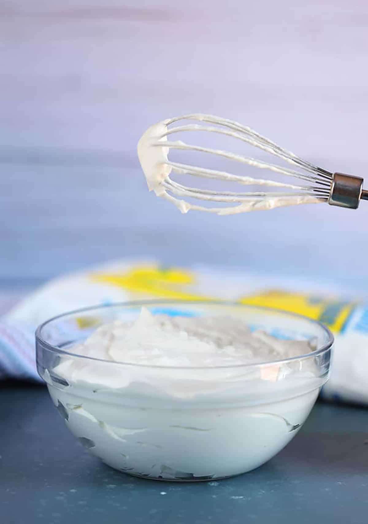Whisk over a bowl of whipped cream in a glass bowl.