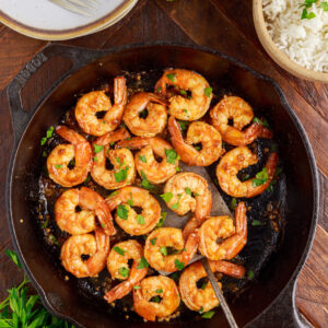 A black pan is filled with cooked shrimp.