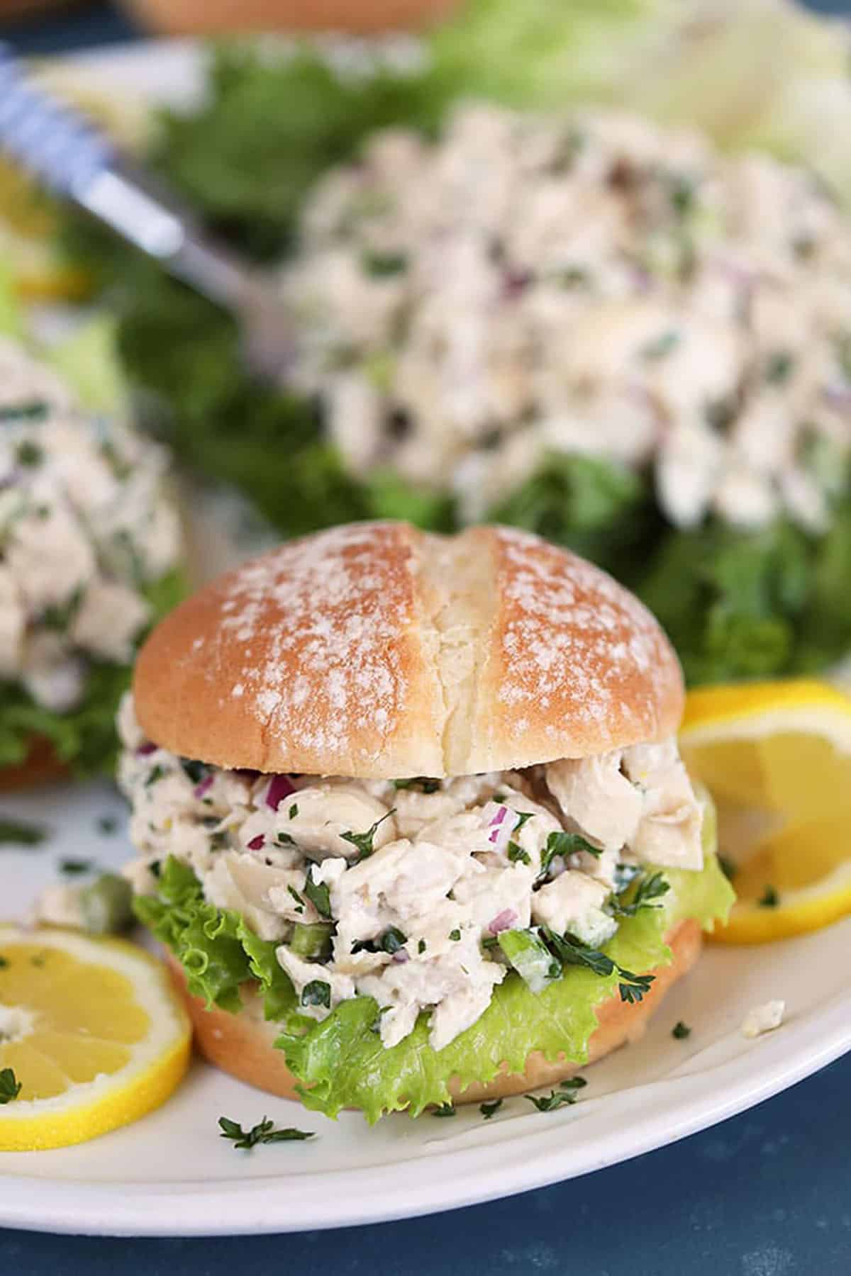 Lemon Tarragon Chicken Salad on a white roll with lettuce and lemon slices 