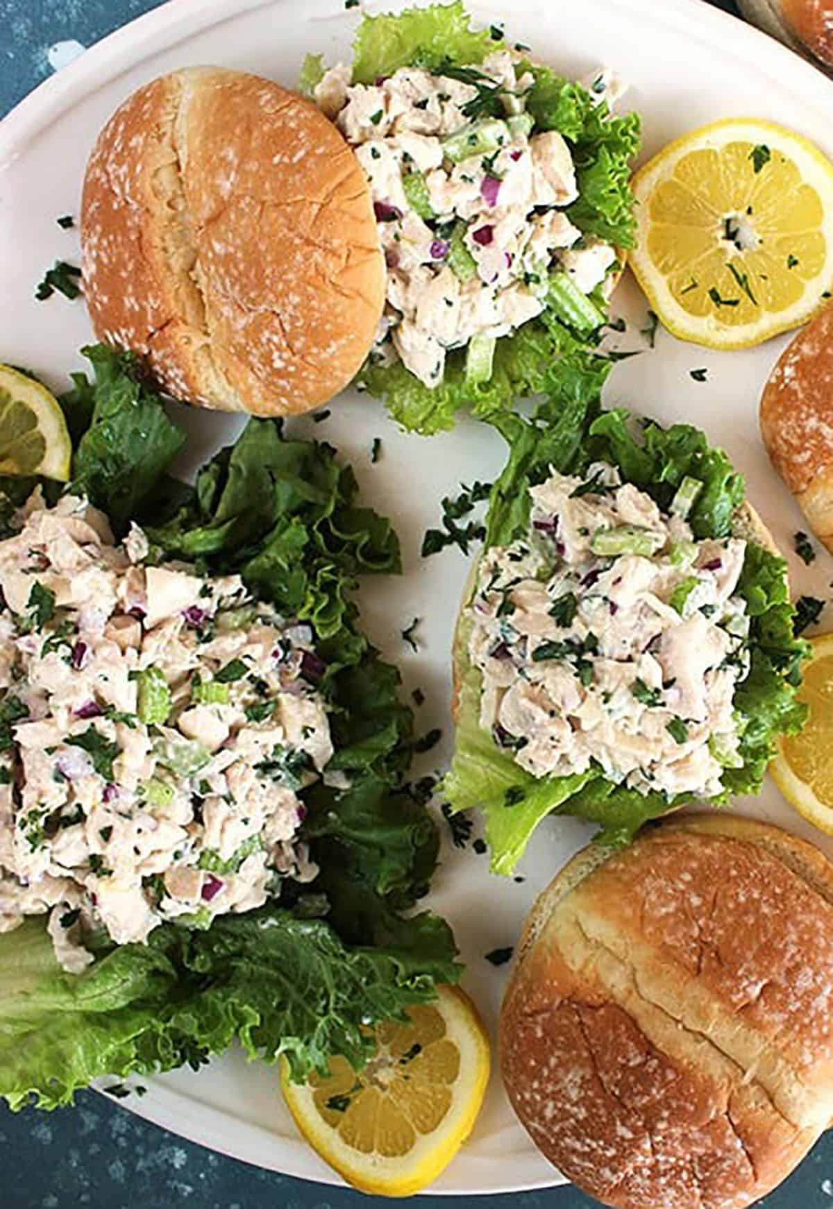Overhead shot of lemon tarragon chicken salad sandwiches on a white platter with a blue background 
