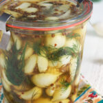 A jar is filled with pickled garlic and dill.