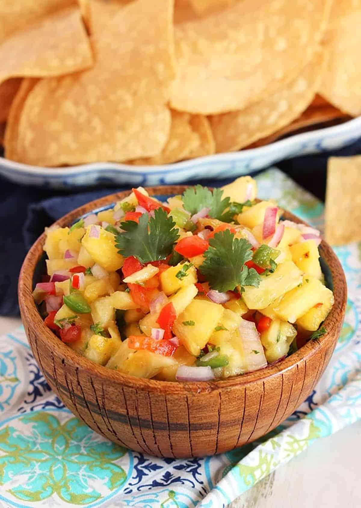 Pineapple Salsa in a coconut bowl with a bowl of tortilla chips in the background.