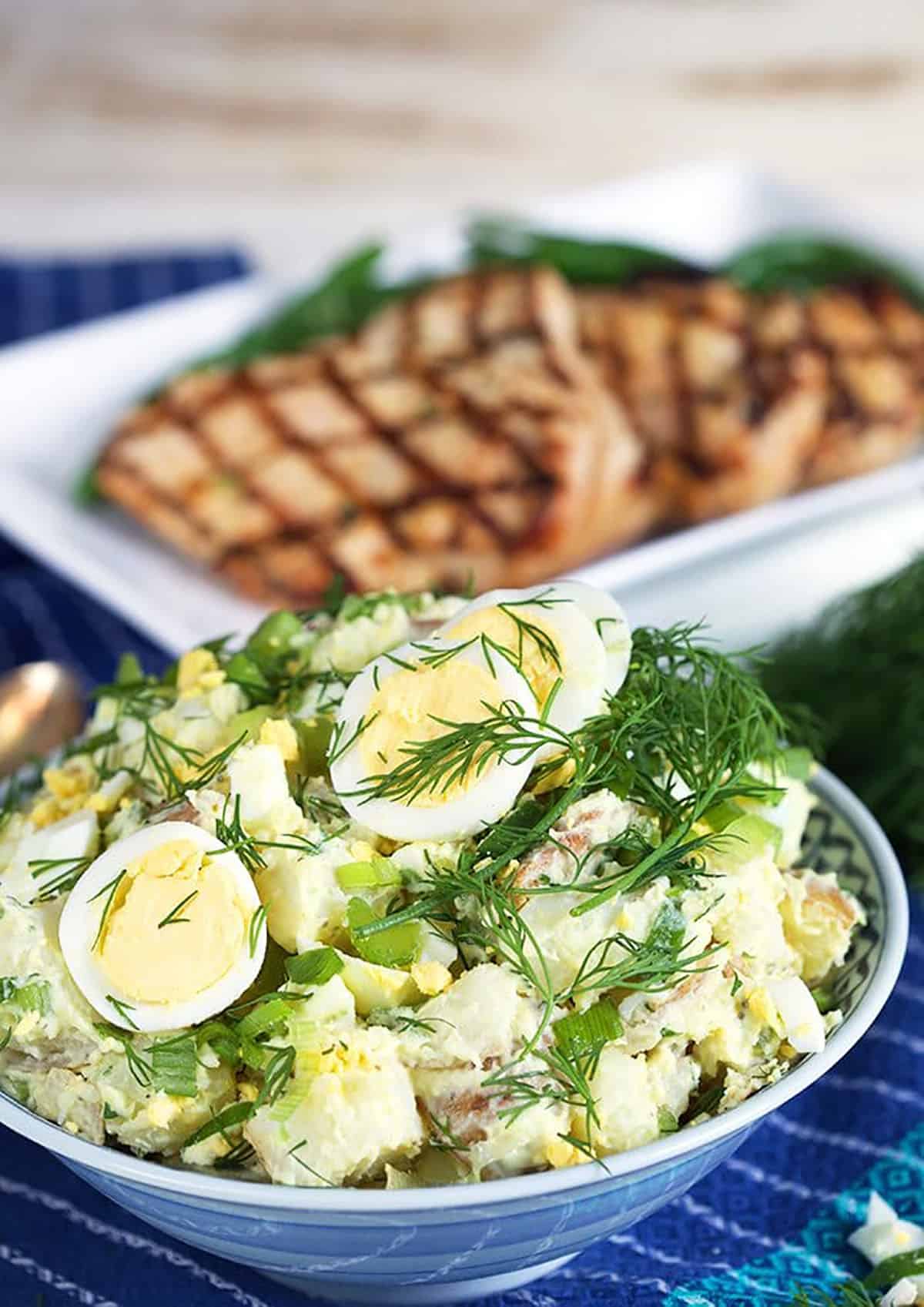 Potato Salad with egg and dill in a blue and white bowl.