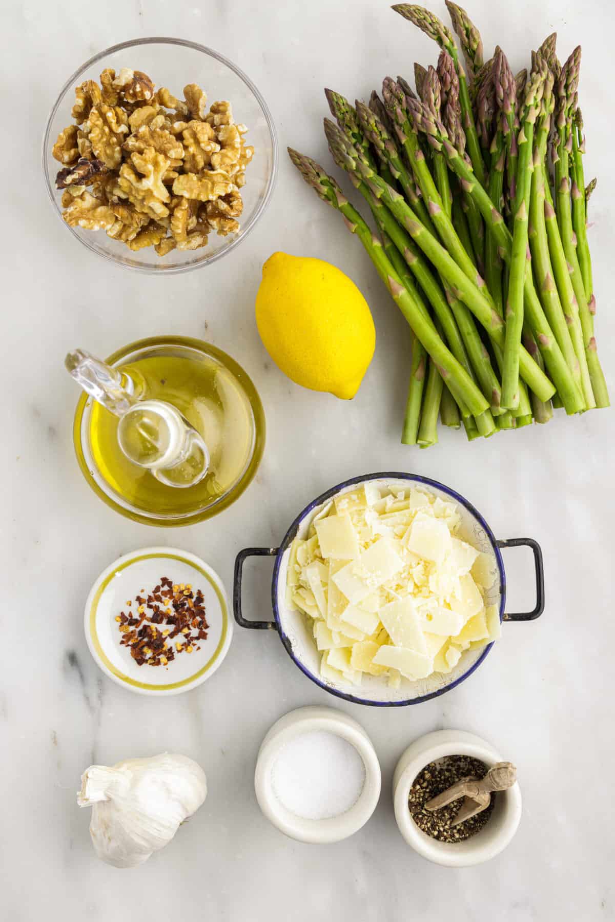 The ingredients for asparagus salad are placed on a white surface.