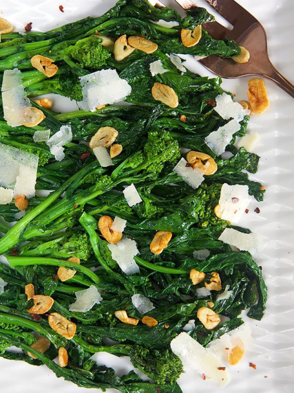 Overhead shot of broccoli rabe with garlic on a white platter.