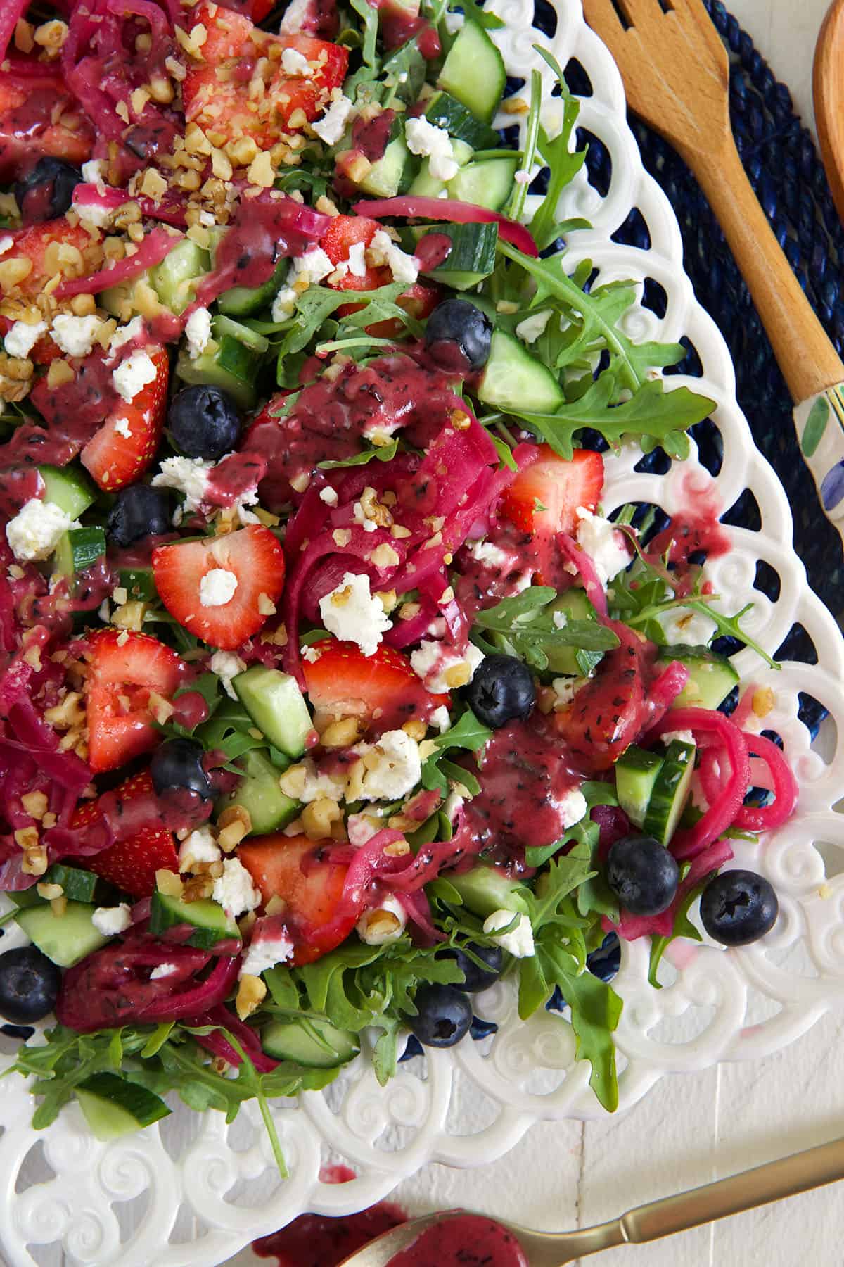 Vinaigrette is drizzled on top of a strawberry arugula salad.