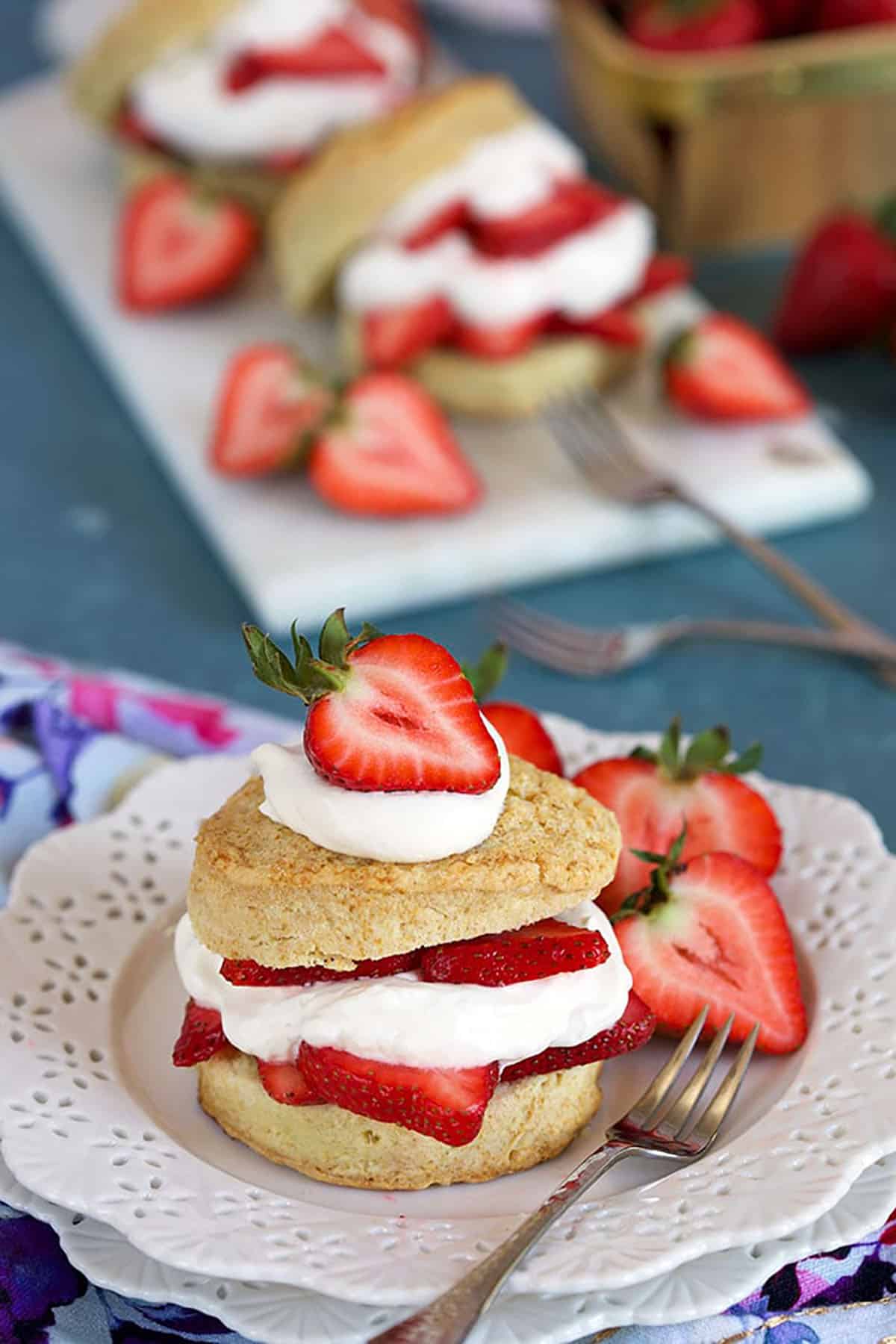 Homemade Strawberry Shortcake on a white plate with a pastry fork on a blue background