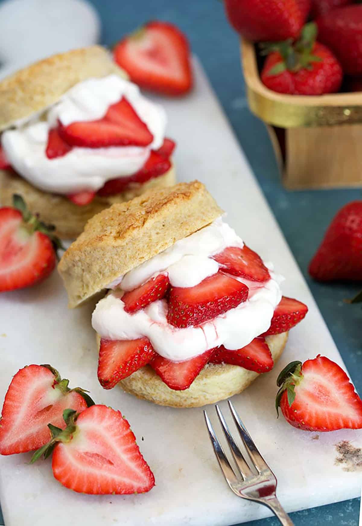 Two of the BEST Strawberry Shortcake recipe on a white marble board on a blue background