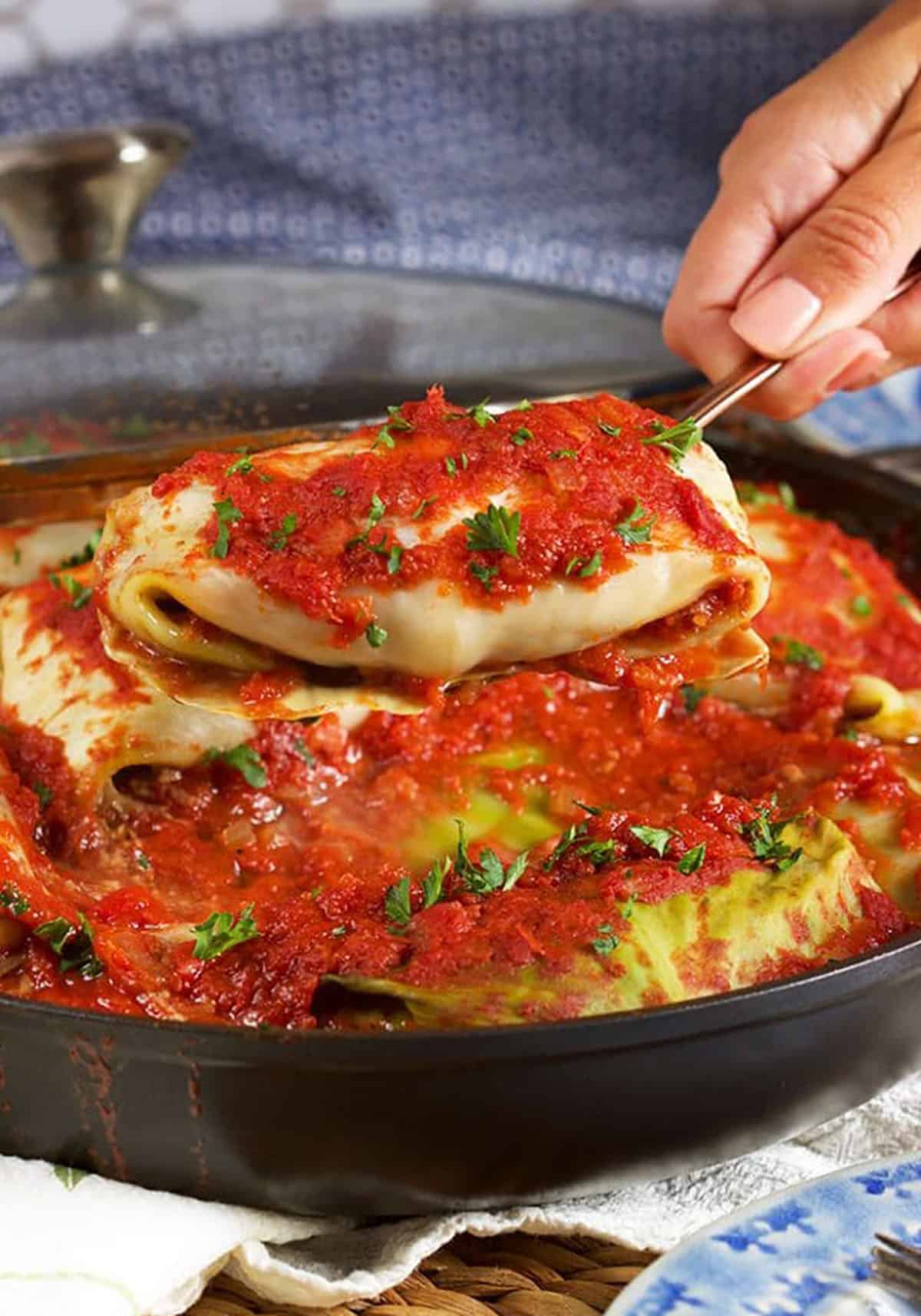 Stuffed cabbage rolls being served from a black pan.