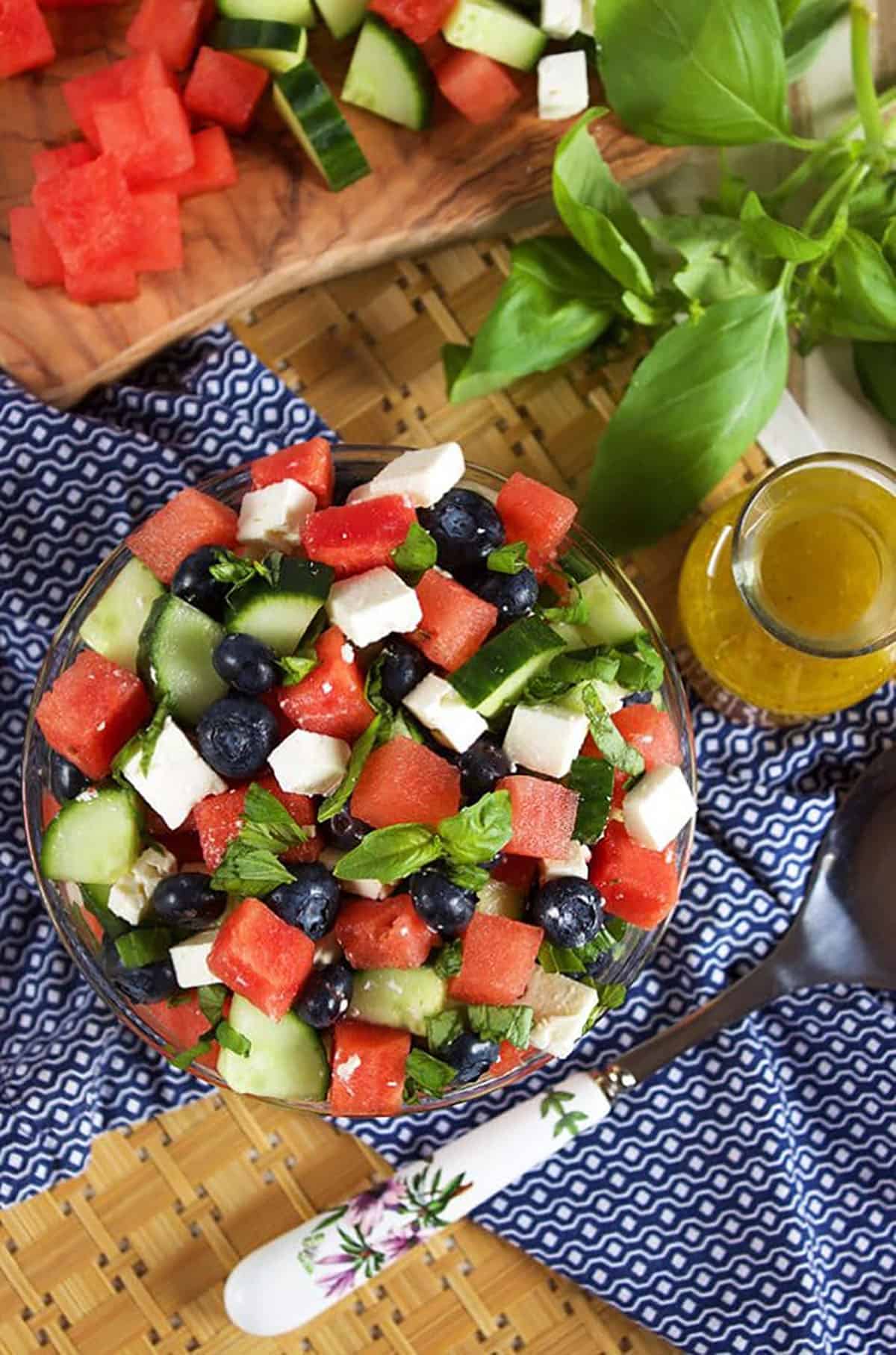 Watermelon feta cucumber salad in a bowl with a board containing chopped watermelon next to it.