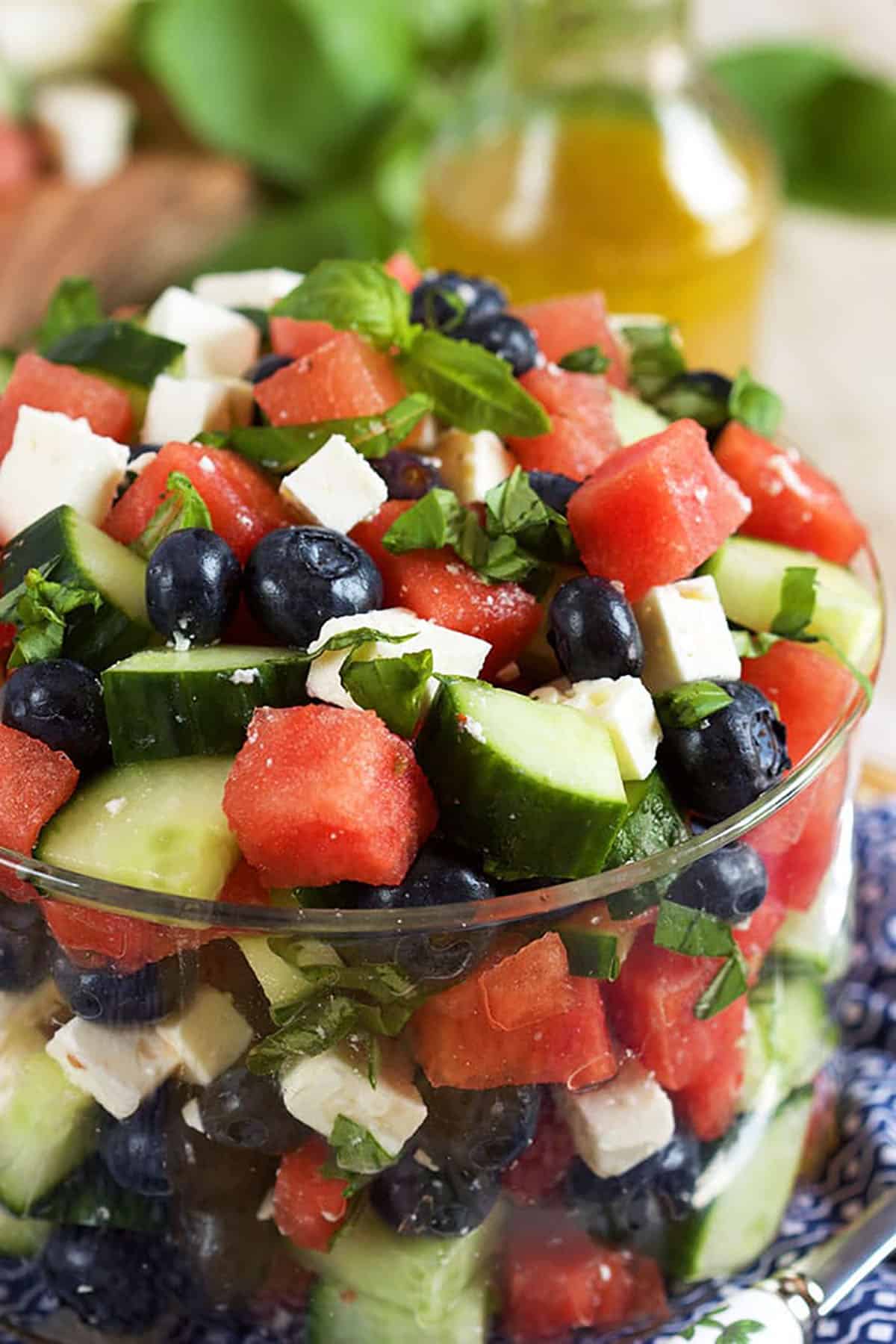 Watermelon feta salad with blueberries and cucumber in a glass bowl with chopped mint on top