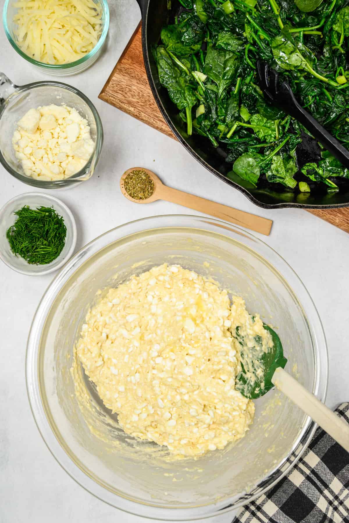 The ingredients for spinach casserole are being mixed in a large bowl.