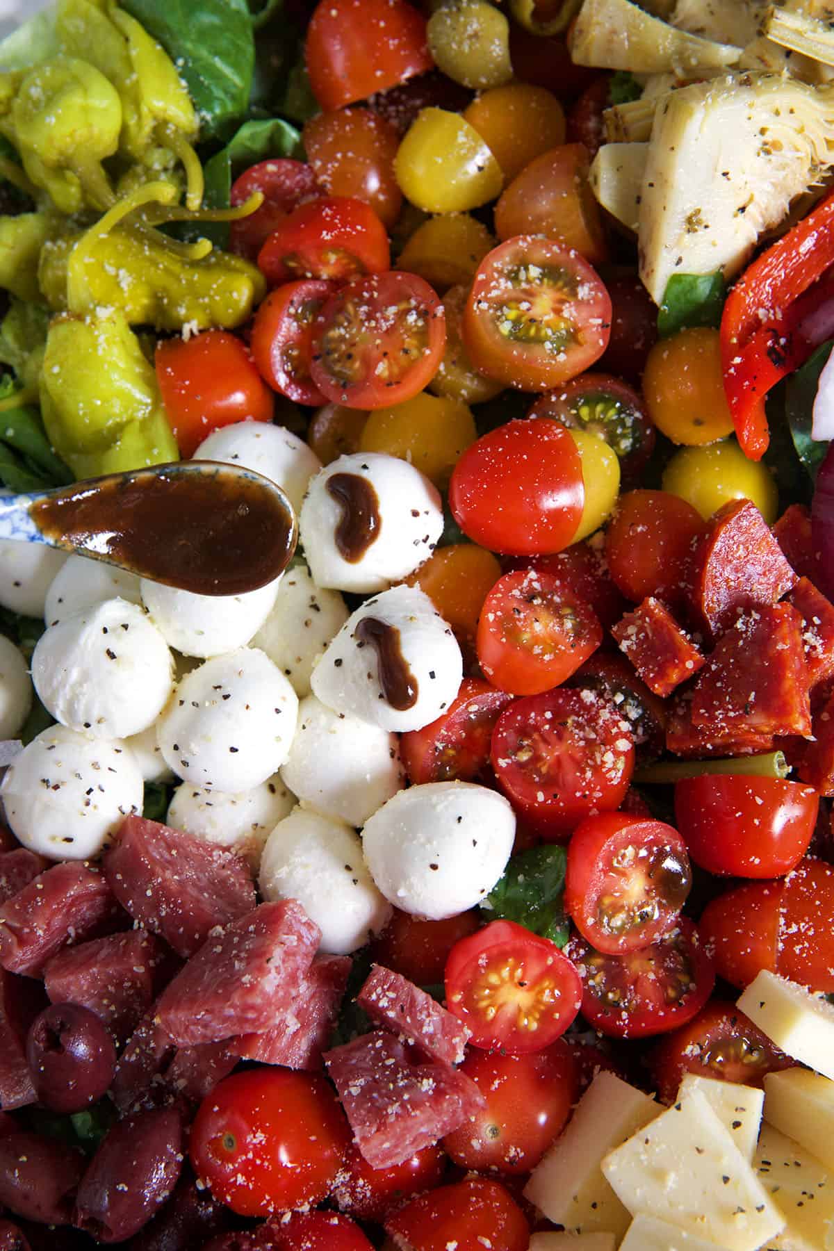 Mozzarella, tomatoes, salami, and pepperocini top a antipasto salad.