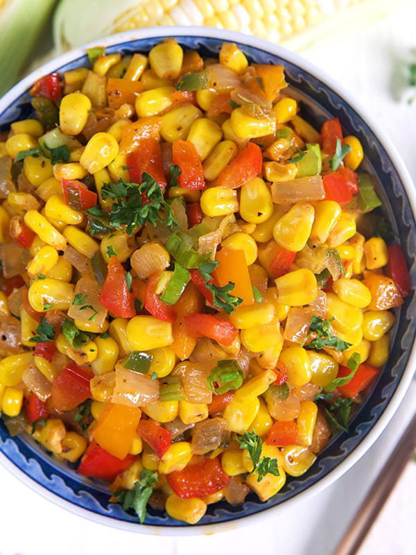 corn Maque Choux in a blue and white bowl on a white background.