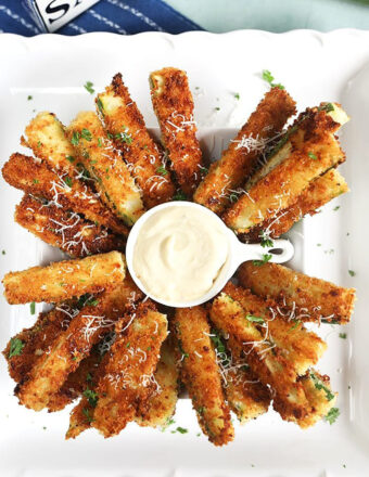 parmesan fried zucchini sticks on a white platter.