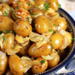 Grilled baby Yukon potatoes on a bowl with garlic and onions.