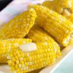 White platter with yellow corn made in the Instant Pot with a pat of butter on them.