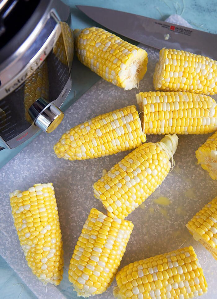 Overhead shot of corn on the cob cut in half in front of an Instant Pot.