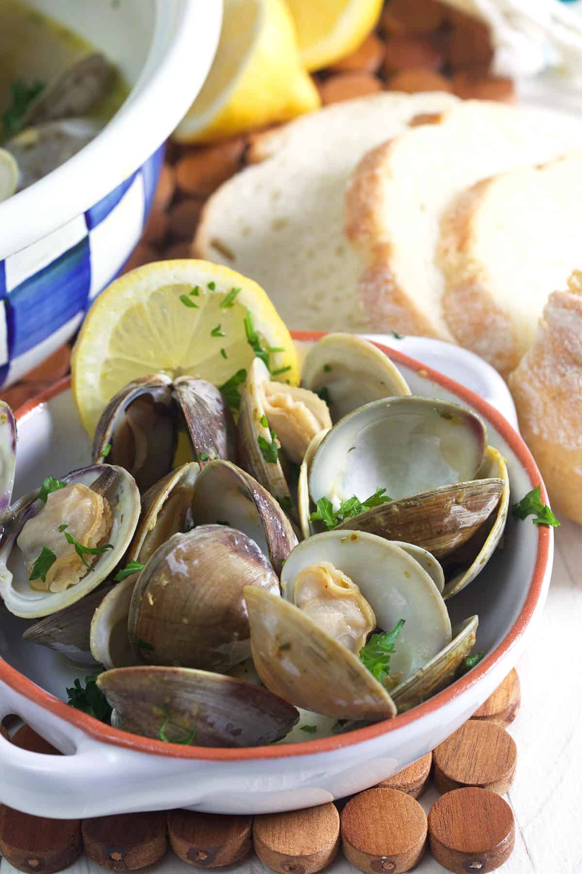 Slices of bread are placed next to a bowl of steamed clams.