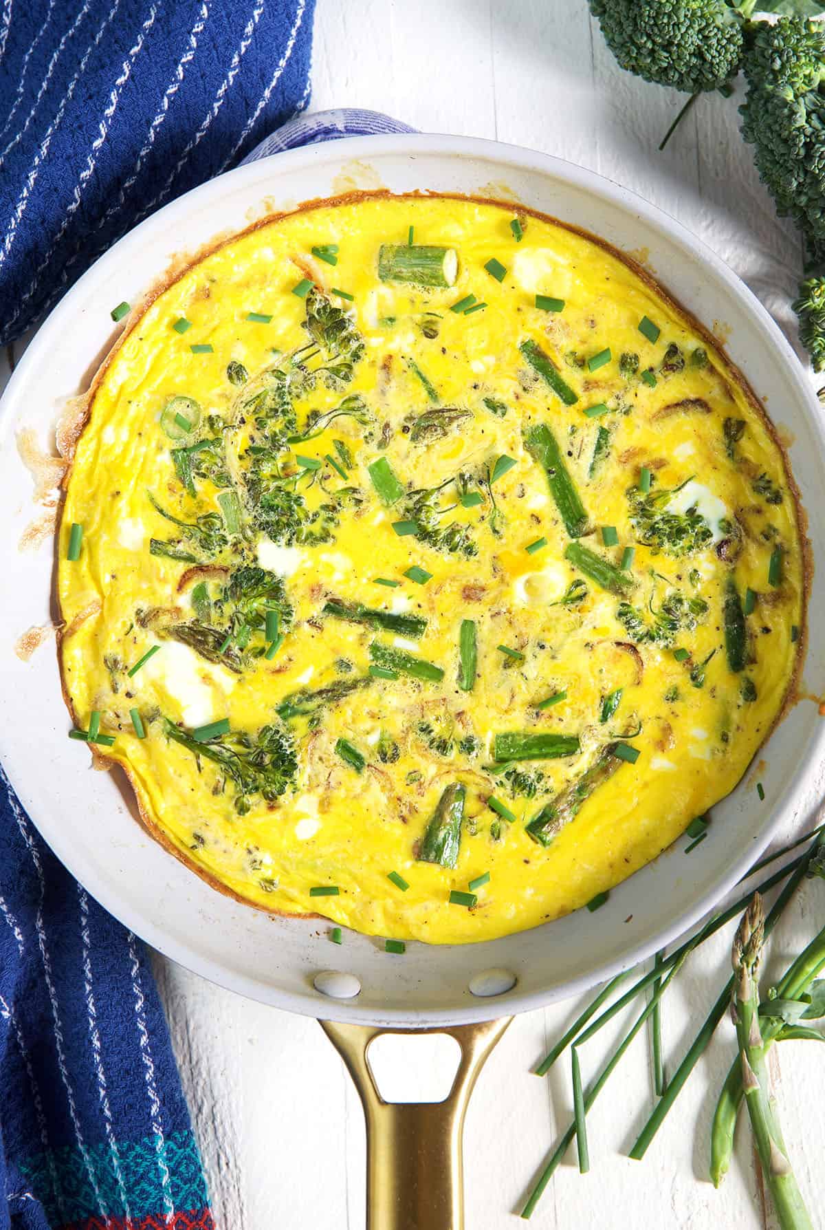 A white pan is filled with baked vegetable frittata.