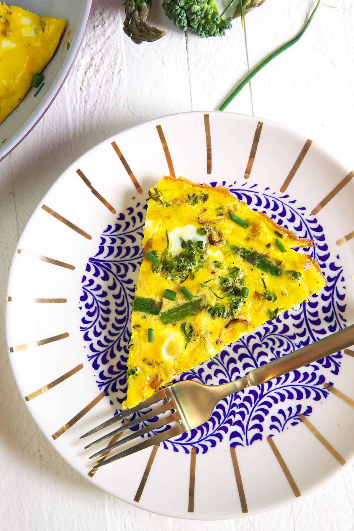 A plate is topped with a single slice of vegetable frittata.